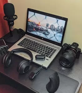 A modern workspace with laptop, camera, and audio equipment on a desk, ideal for creative projects.